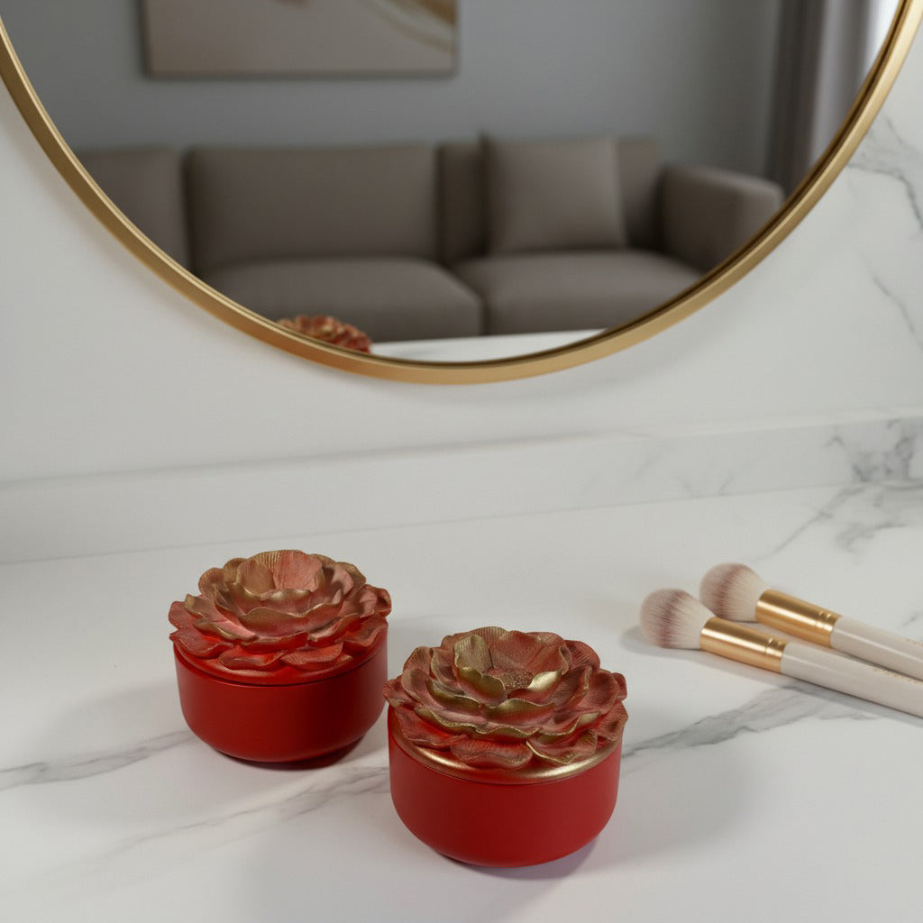 Red floral candles on a marble surface with makeup brushes and a mirror in the background.