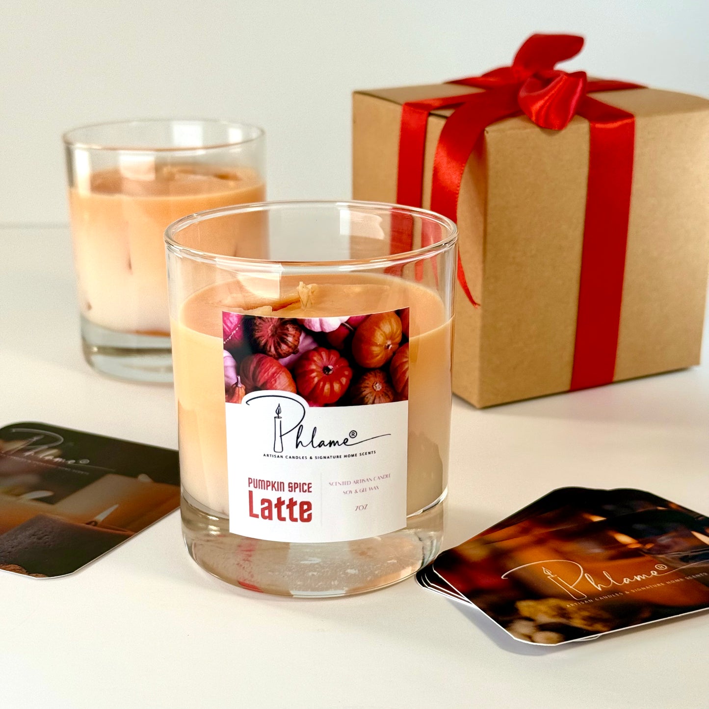 Candle labeled 'Pumpkin Spice Latte' with a gift box and coasters on a light background