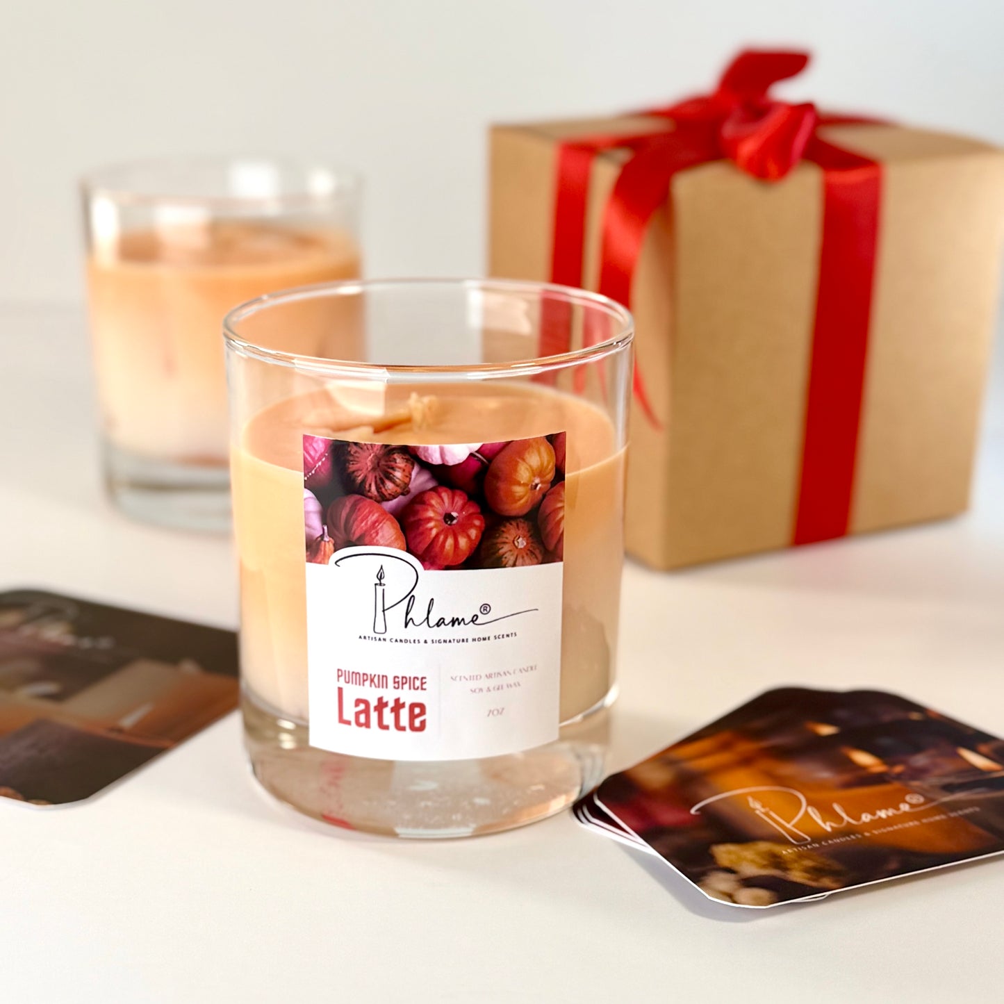 Candle with pumpkin spice latte label and gift box in the background