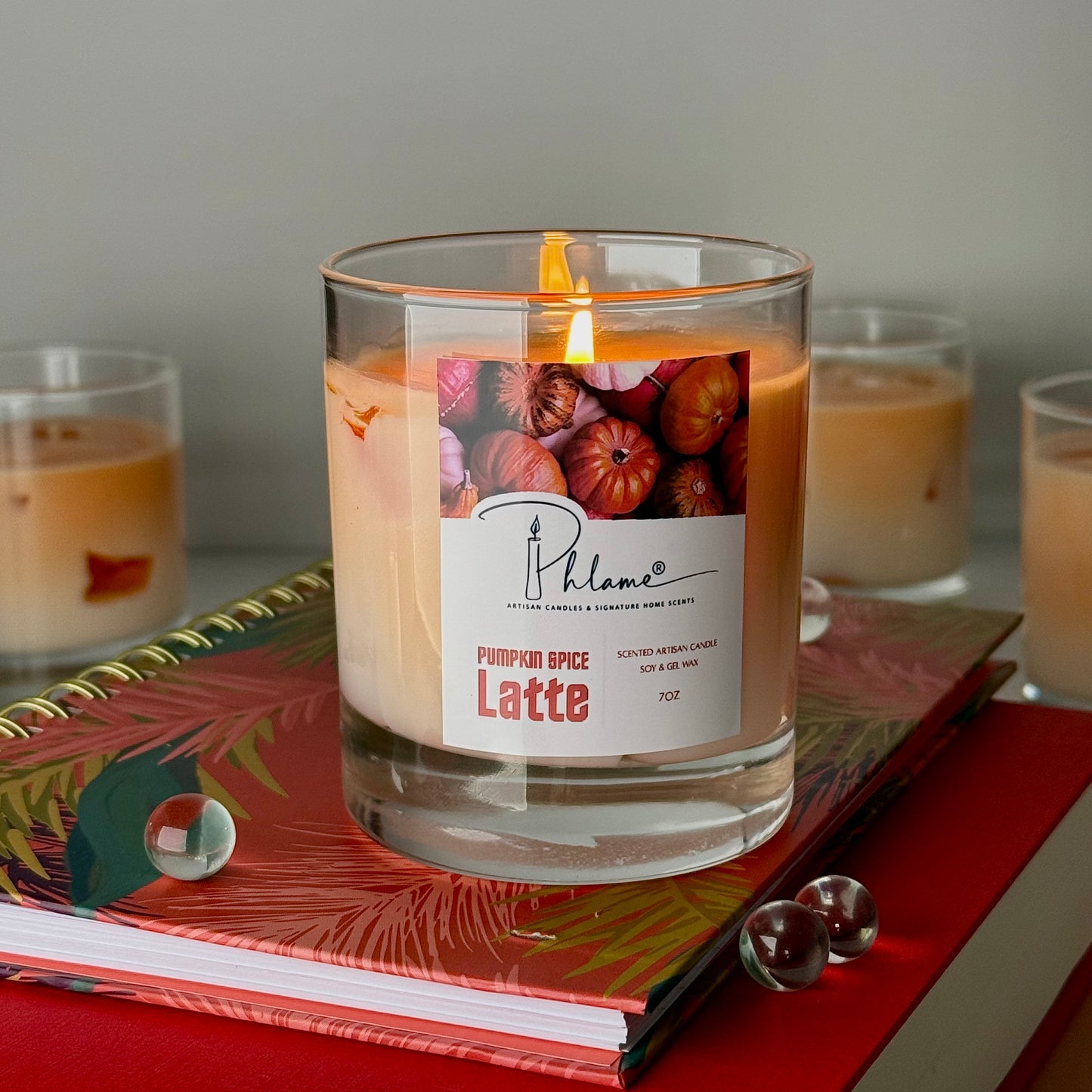 Candle labeled 'Pumpkin Spice Latte' on a decorative surface with other candles in the background.