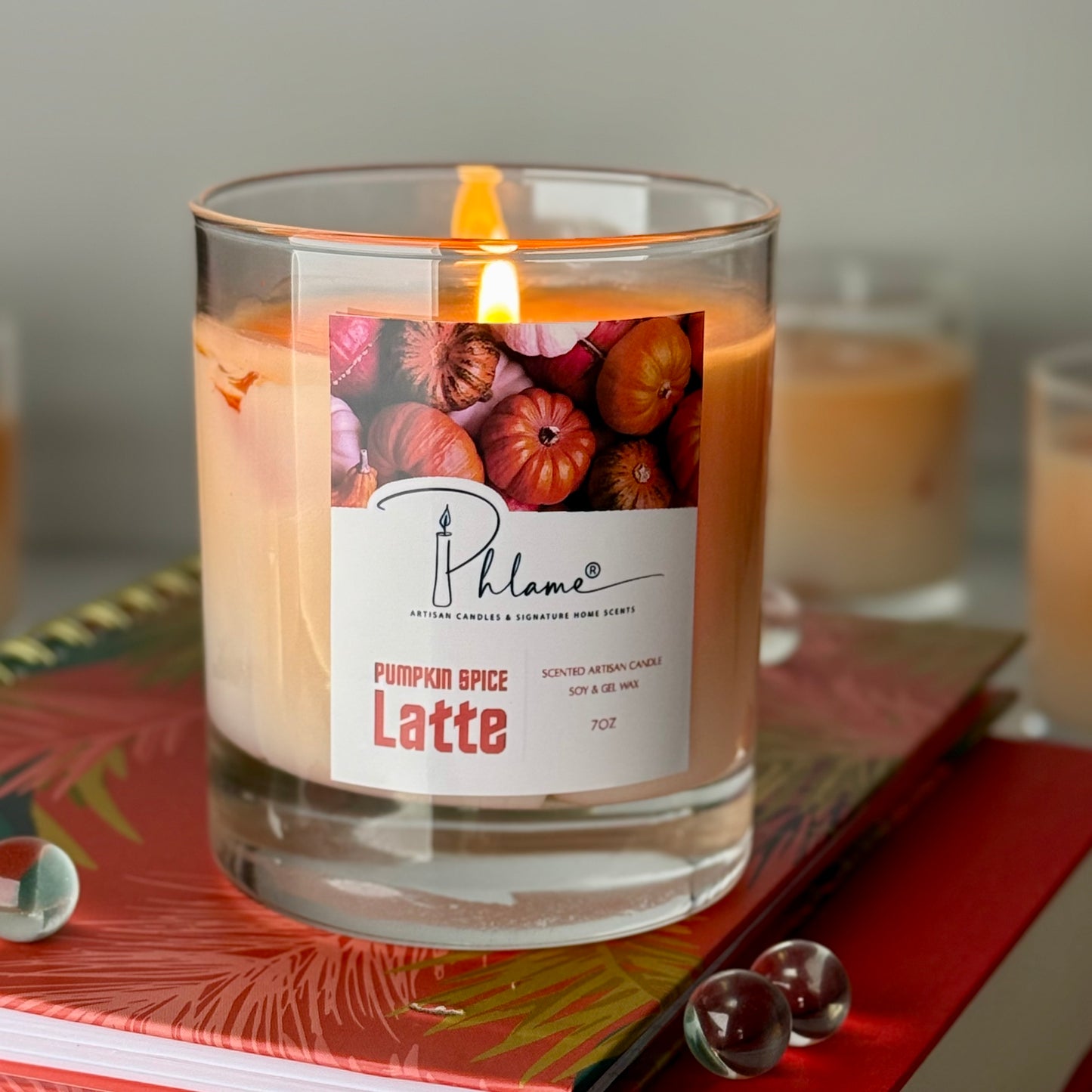 Candle labeled 'Pumpkin Spice Latte' with a Phlame brand on a decorative surface.