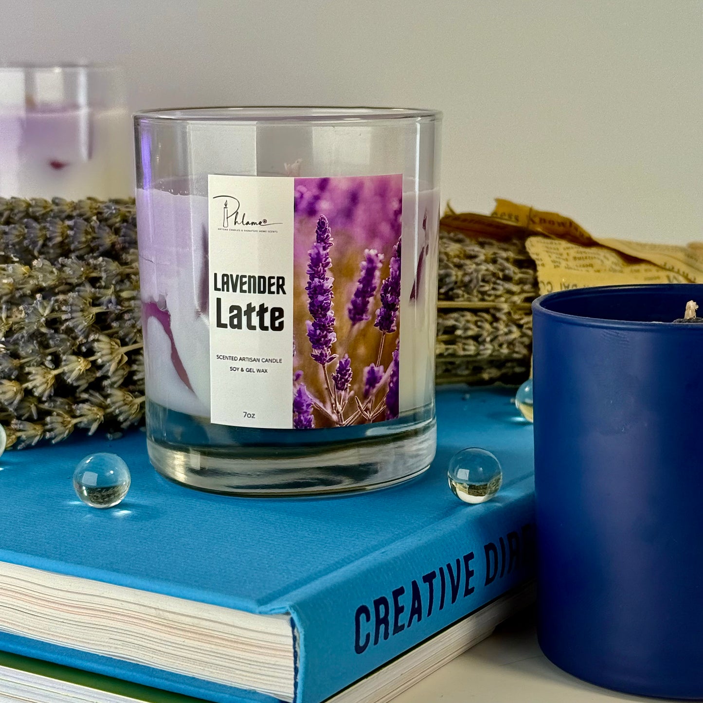 Lavender Latte candle on a blue book with a blue candle next to it