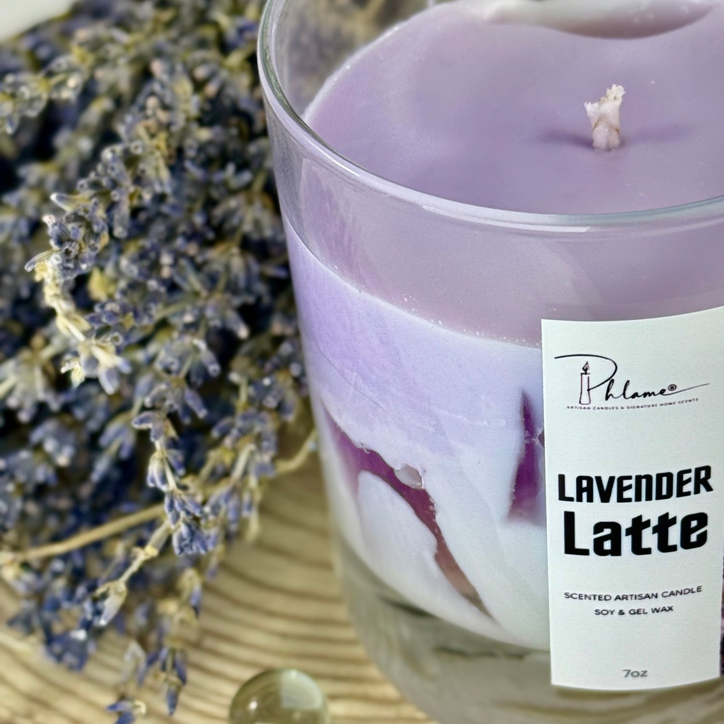 Lavender latte candle with a label and lavender flowers in the background