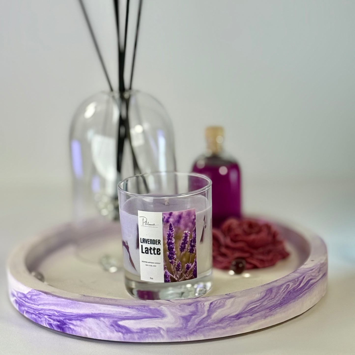 Candle labeled 'Lavender Latte' on a purple and white marbled tray with a blurred background