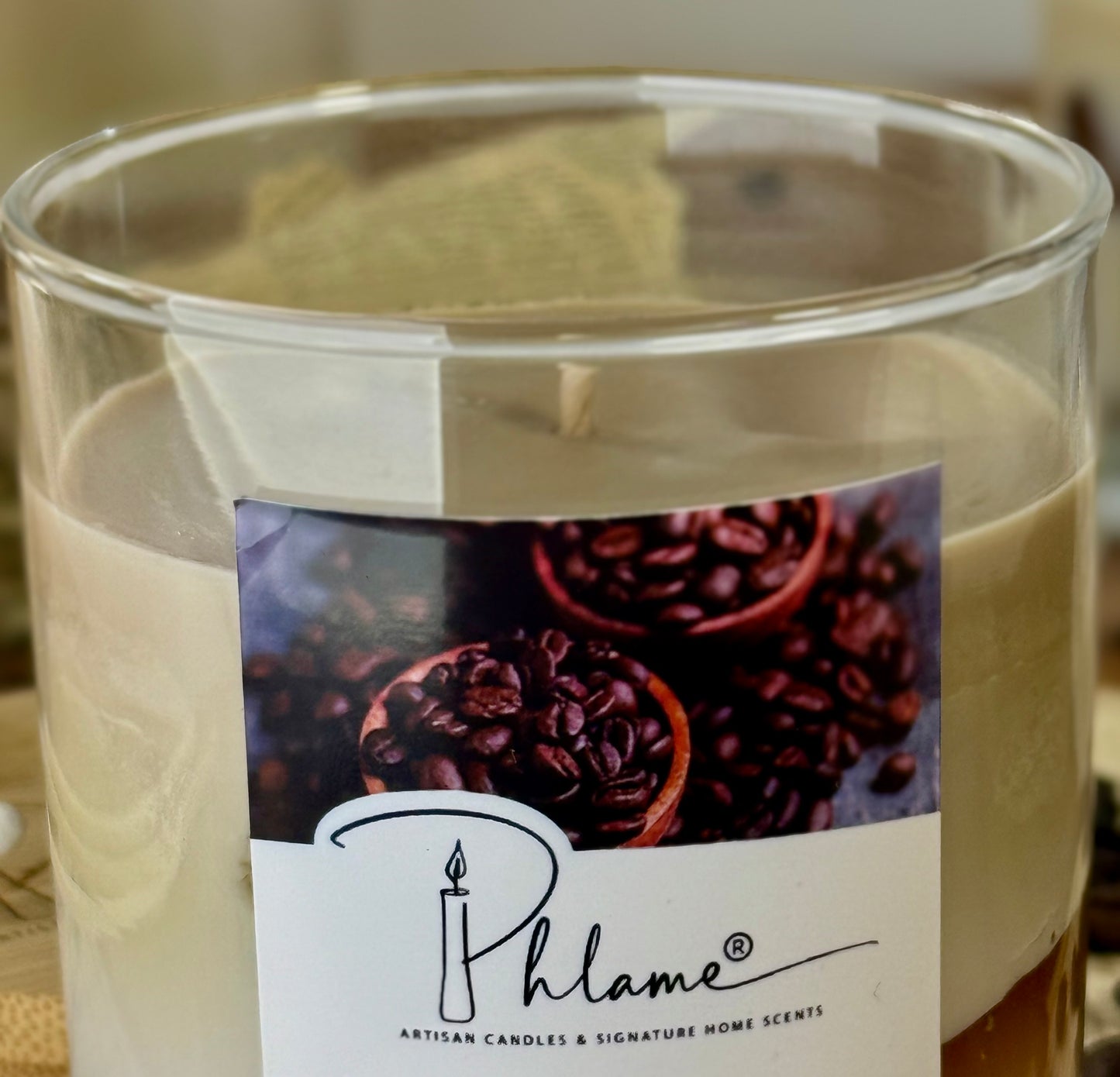 Candle with a label featuring coffee beans and the brand 'Phlame'.