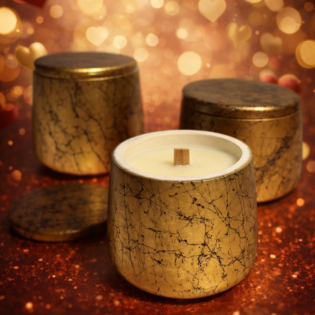 Decorative candles with a textured gold finish on a warm, blurred background with heart shapes.