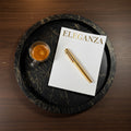 Black marble tray with a cup of coffee, notebook, and pen on a wooden surface