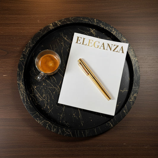 Black marble tray with a cup of coffee, notebook, and pen on a wooden surface
