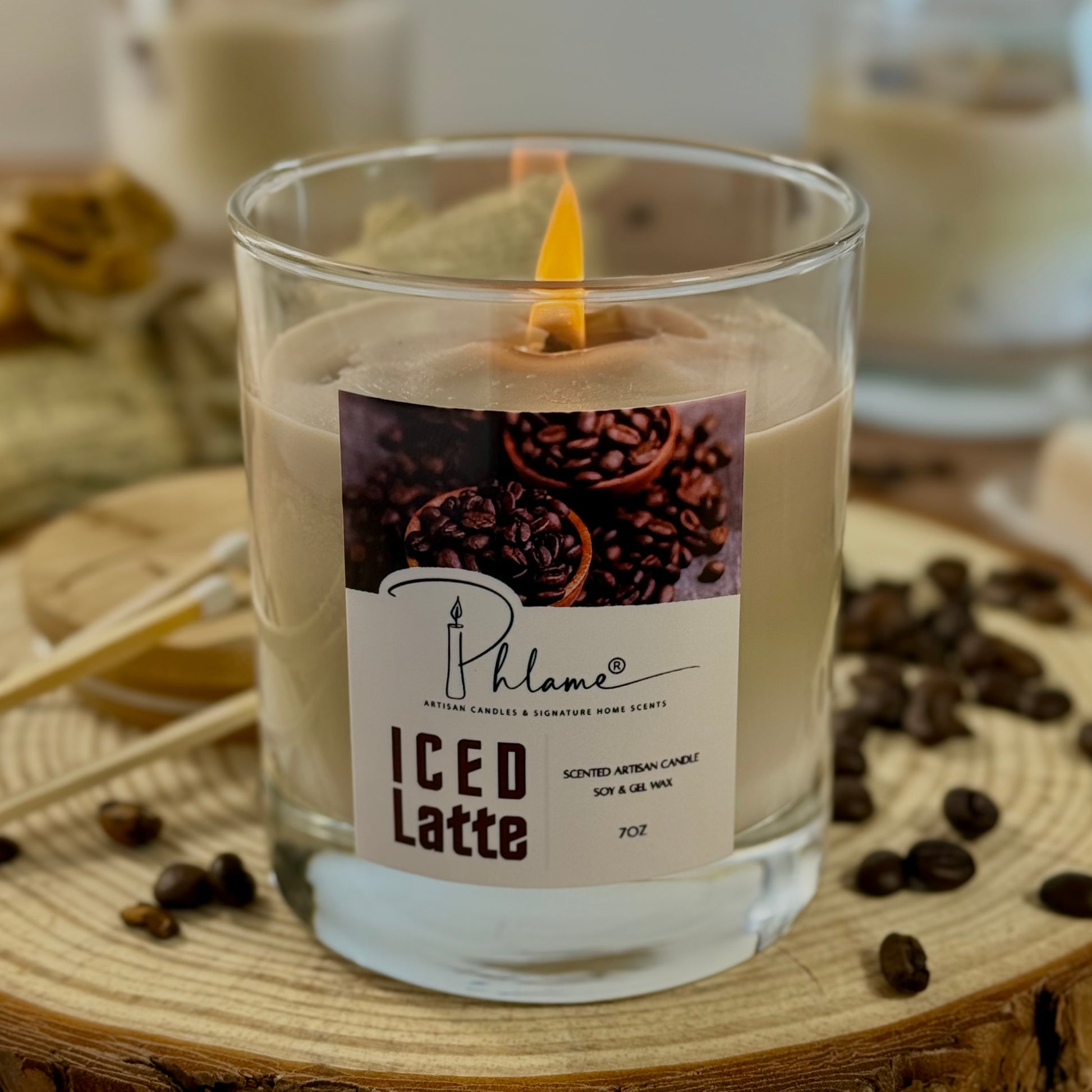 Candle labeled 'ICED LATTE' with coffee beans around on a wooden surface
