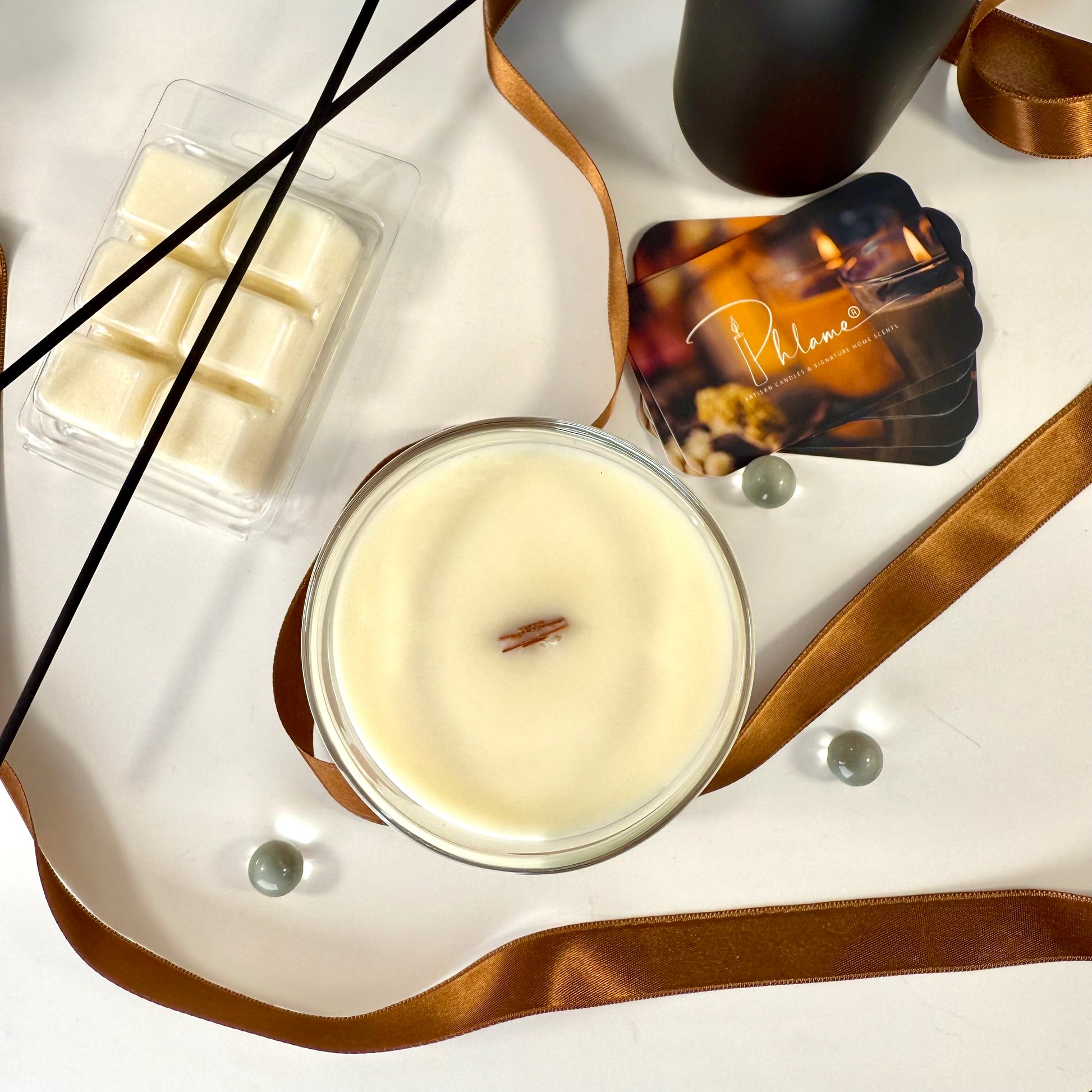 Candle with packaging and decorative elements on a white surface