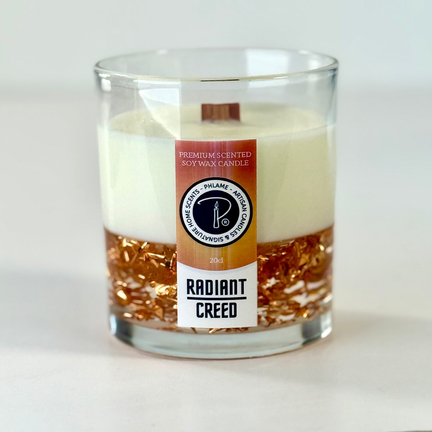 Radiant Creed candle with layered wax and wooden wick in black gift box, styled with citrus and spices.