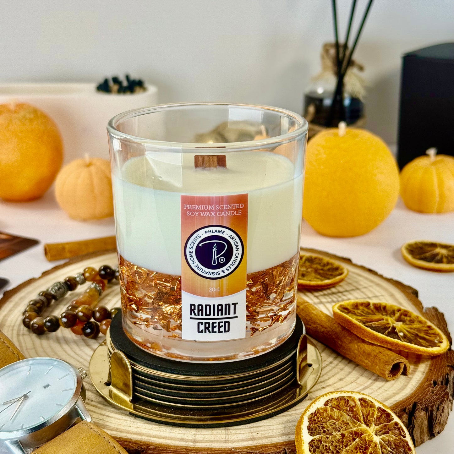 Radiant Creed candle with layered wax and wooden wick in black gift box, styled with citrus and spices.