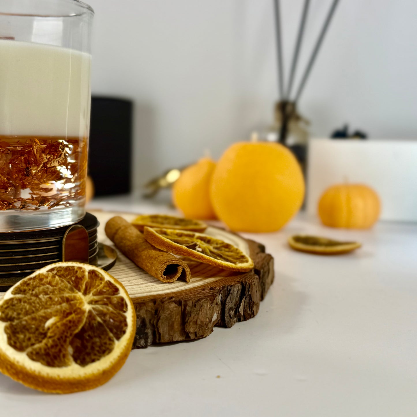 Radiant Creed candle with layered wax and wooden wick in black gift box, styled with citrus and spices.