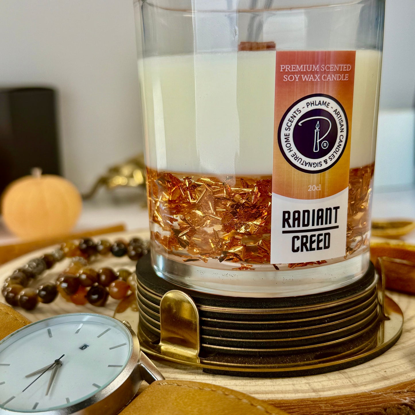 Radiant Creed candle with layered wax and wooden wick in black gift box, styled with citrus and spices.