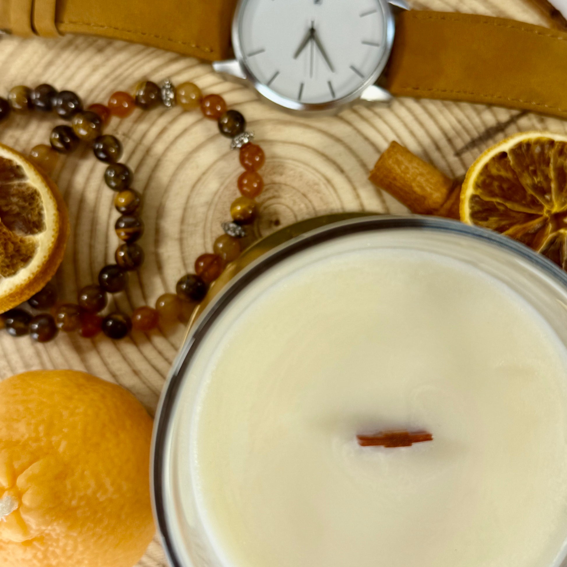 Candle, watch, and dried oranges on a wooden surface