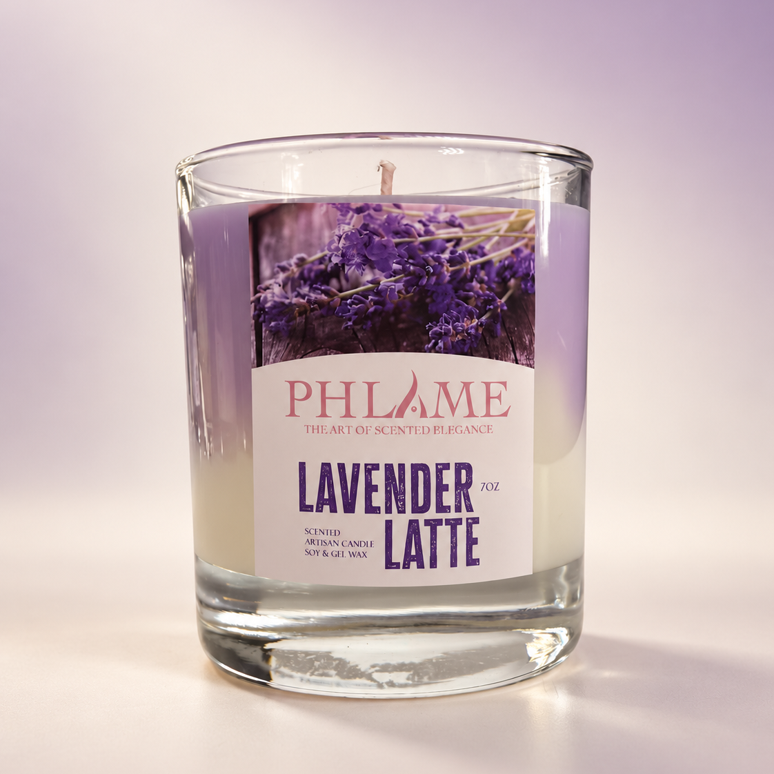 A PHLAME brand scented candle in a clear glass jar, labeled 'Lavender Latte'. The candle features a light purple wax body with a prominent white label depicting purple lavender flowers.