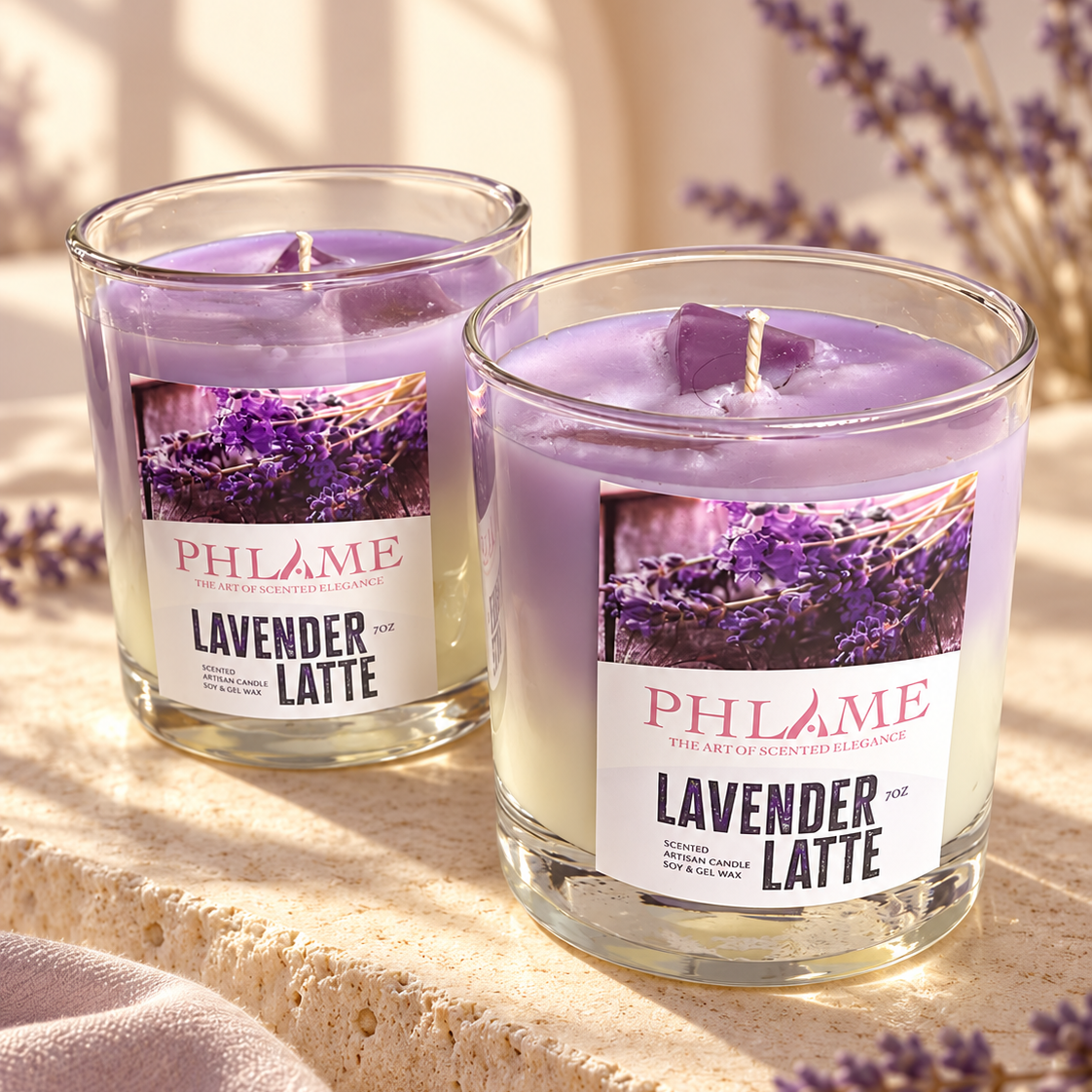 Two PHLAME Lavender Latte scented candles in clear glass jars, styled on a textured stone surface with lavender sprigs and warm sunlight.