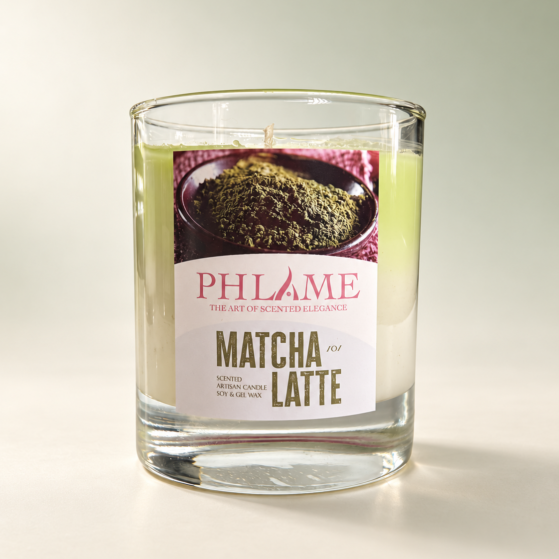 A PHLAME Matcha Latte scented candle in a clear glass jar, featuring a white label with a matcha tea illustration and the brand name PHLAME.